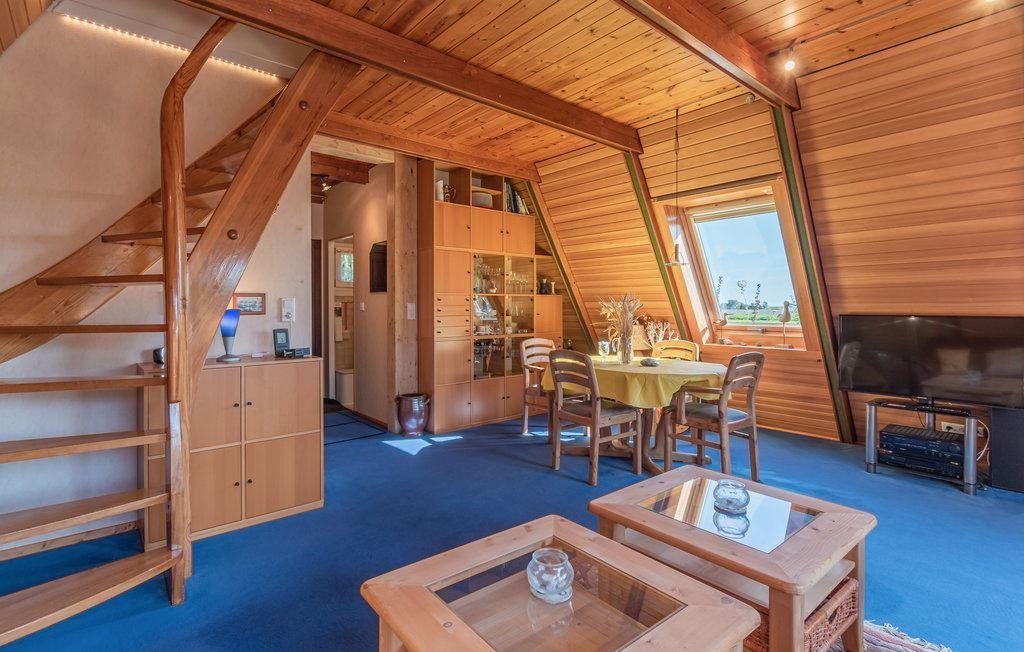 Wohnraum mit Holzdecke, Treppe und Esstisch unter Dachschrägen.