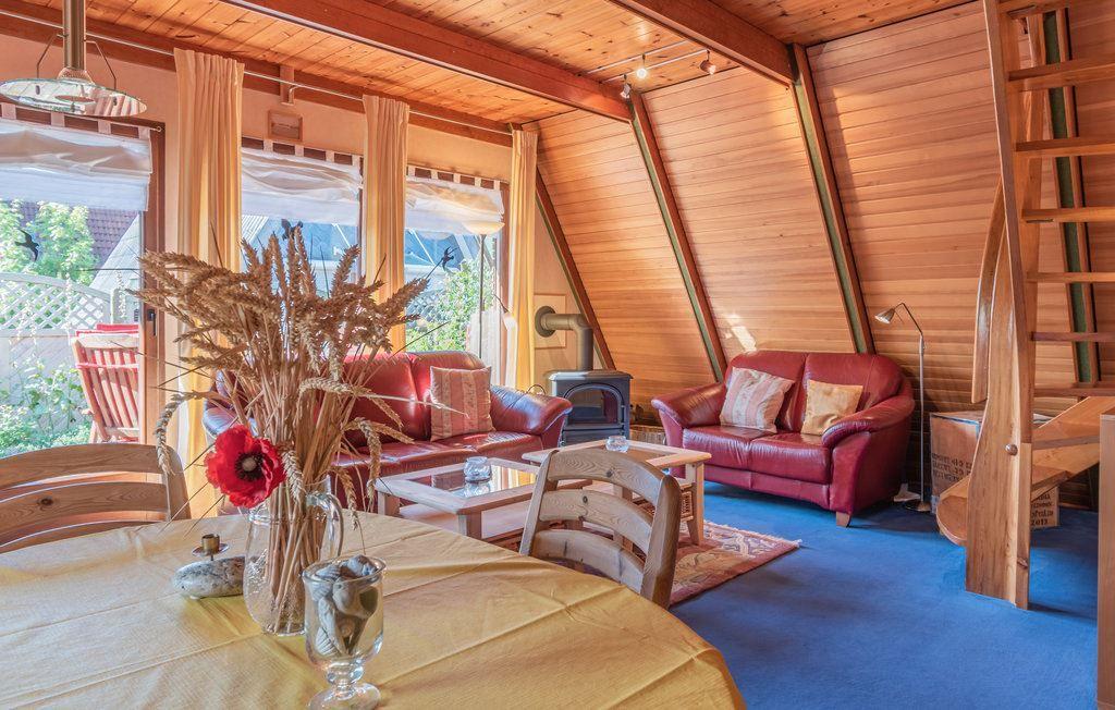 Wohnraum mit Holzwänden, rotem Sofa, Esstisch und Holztreppe.