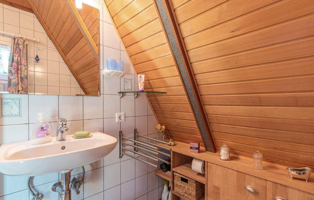 Bad mit Waschbecken, Spiegel und Holzwand unter Dachschräge.