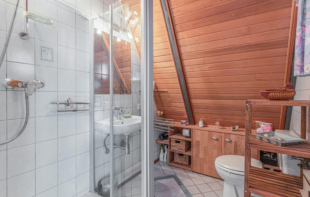 Badezimmer mit Dusche, Waschbecken und Toilette. Holzwände und -möbel.