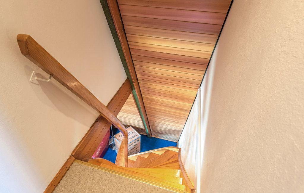 Holzgetreppe mit Geländer führt zu einem Dachboden mit Holzdecke.