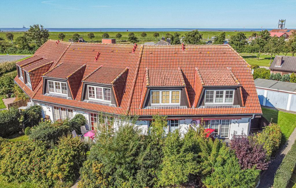 Haus mit rotem Ziegeldach und Gartenterrasse, Blick auf Grünflächen und Meer.
