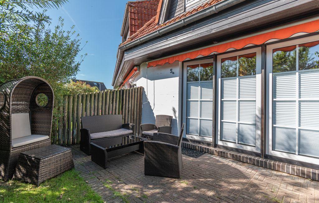 Terrasse mit Gartenmöbeln, Sitzgelegenheiten und Holzzaun. Haus mit Fenstern und Dach.