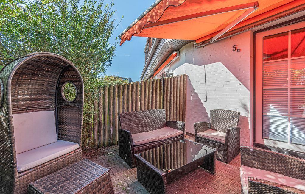 Terrasse mit Rattanmöbeln, Sonnenschutz und Gartenzaun. Hausnummer 5a an der Wand.