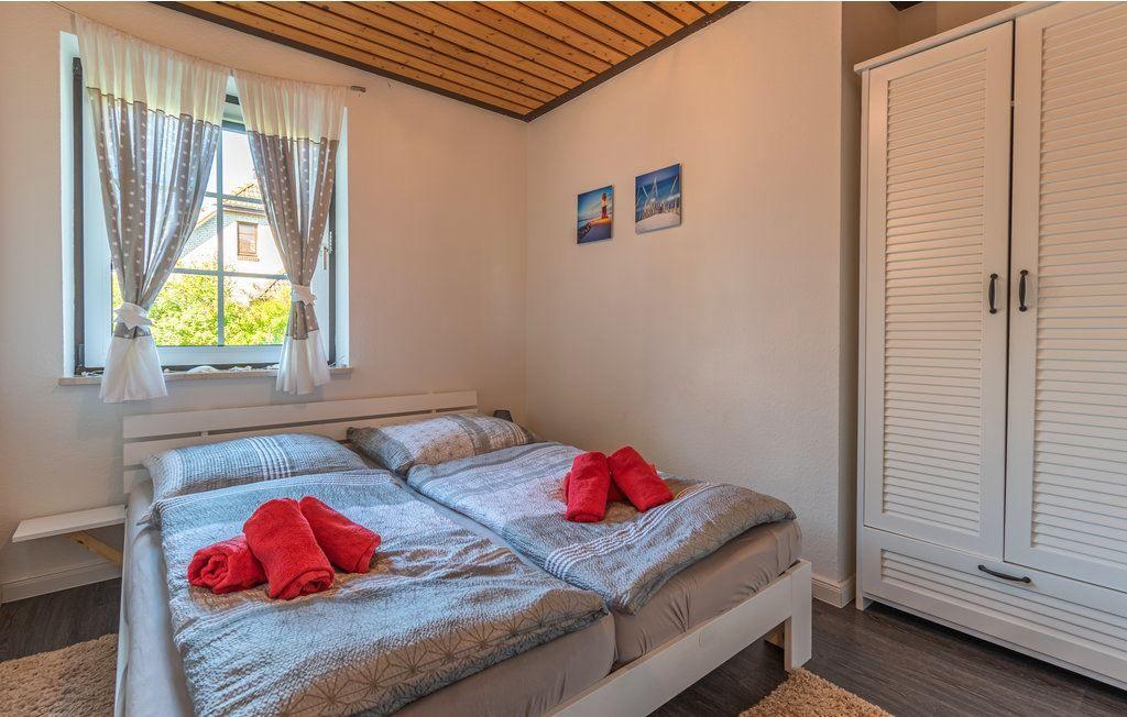 Zimmer mit Doppelbett, Fenster mit Vorhängen und weißen Schwebetüren.