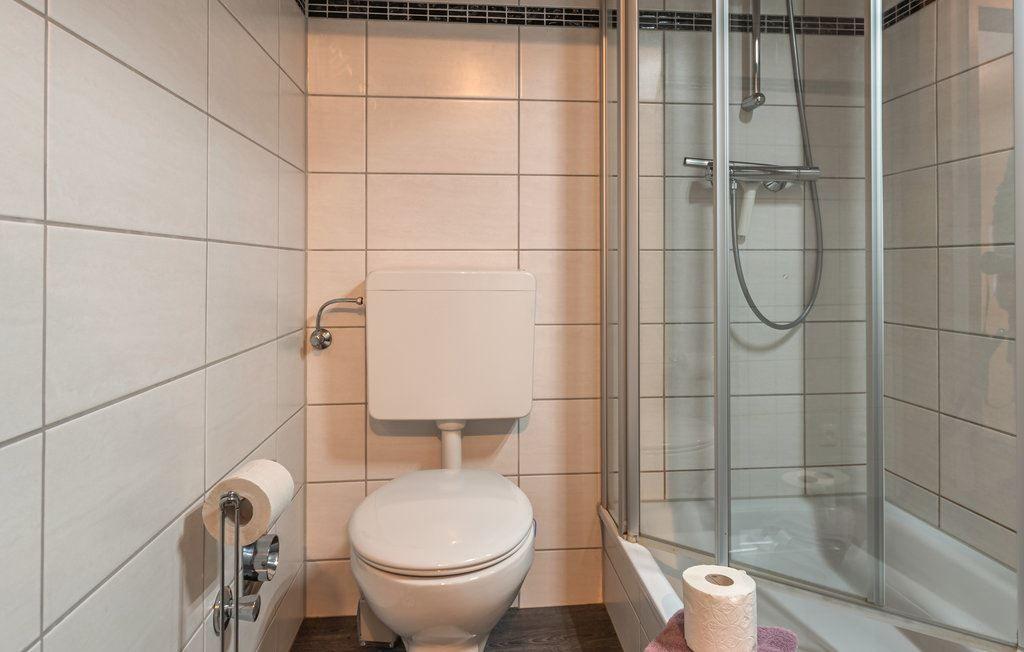 Badezimmer mit Toilette und Dusche mit Glaswand