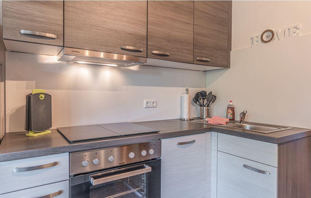 Küche mit Holzschränken, Herd und Spüle