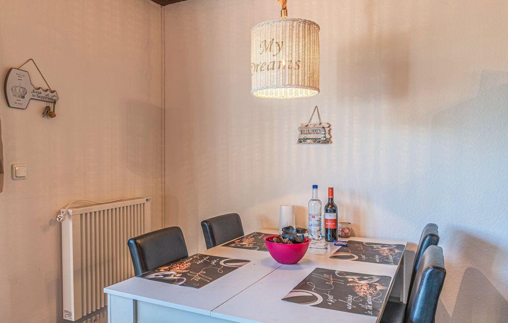 Esszimmer mit Tisch, Stühlen und Deckenleuchte. Wanddekoration und Heizung sind sichtbar.