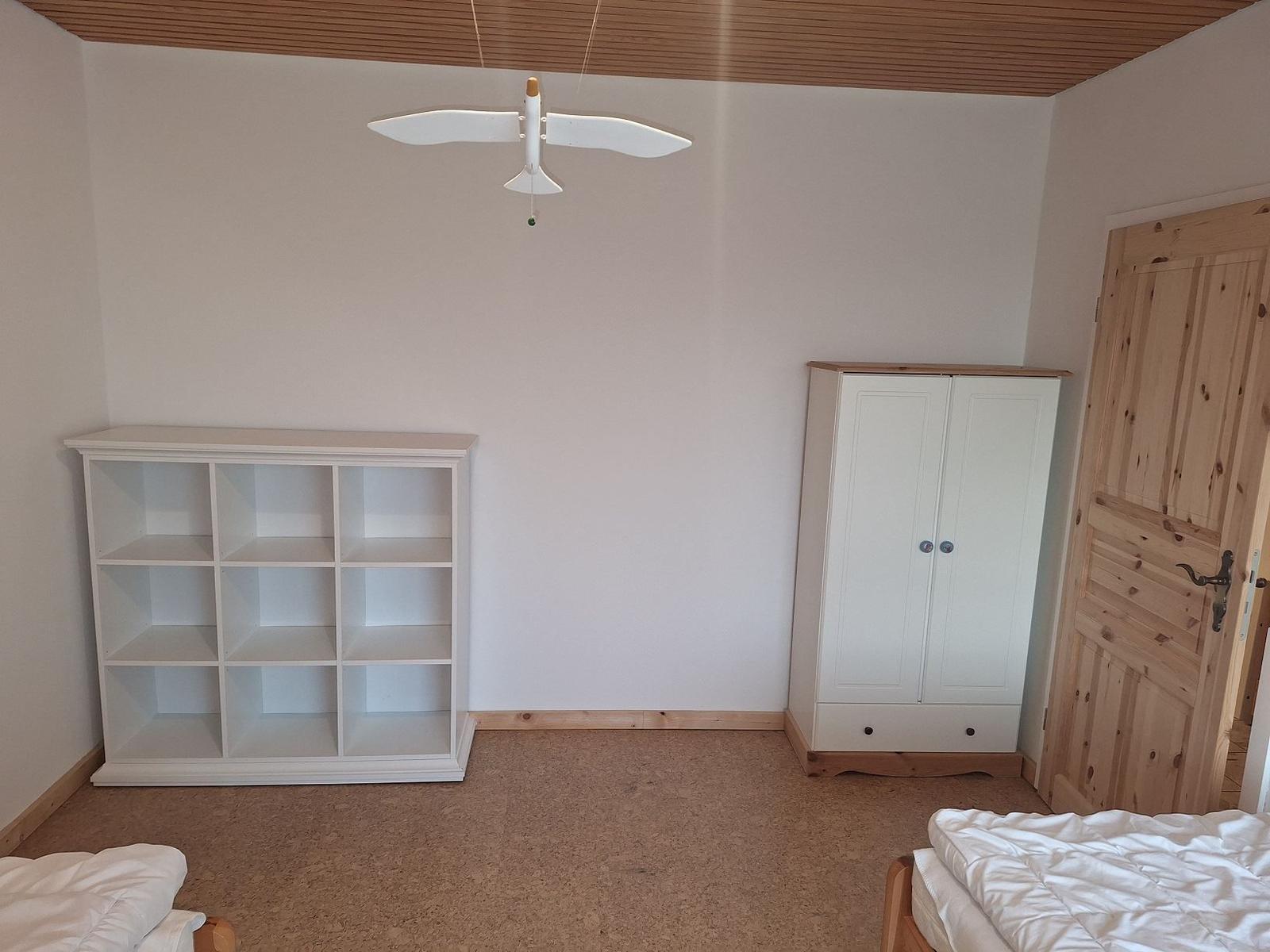 Schlafzimmer mit Bett, Kleiderschrank und Regal. Deckenventilator in Form eines Flugzeugs.