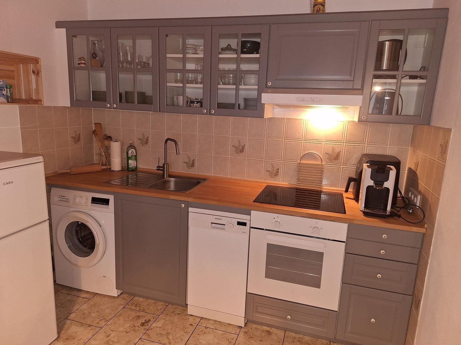 Küche mit grauen Schränken, Spüle, Kochfeld und integrierten Geräten.