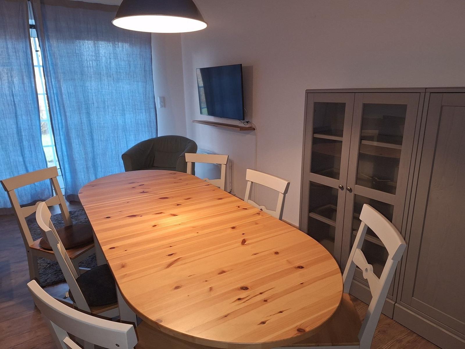 Esszimmer mit Holztisch, Stühlen, Fernseher und Schrank.