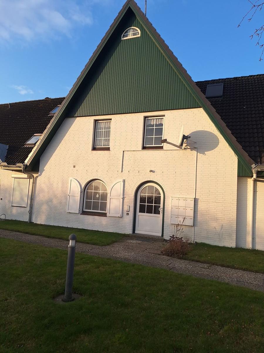 Haus mit weißem Putz, grünem Dach und arkgelbem Eingangsbereich.