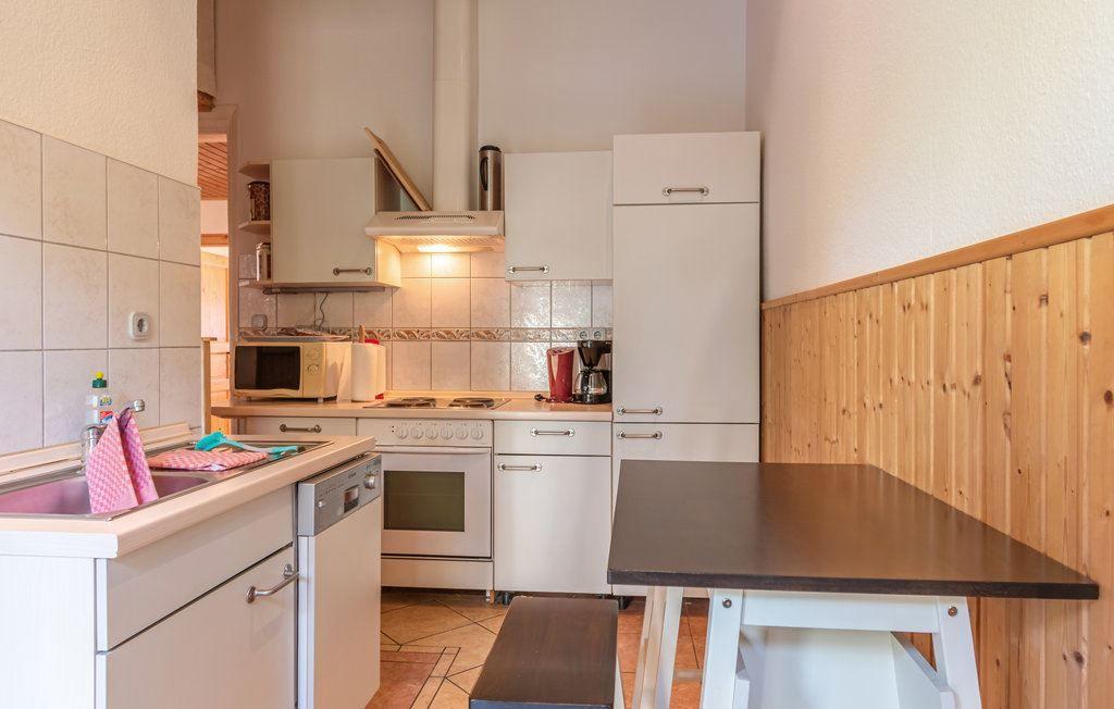 Küche mit weißer Einbauküche, Spüle, Herd und Esstisch mit Bank.