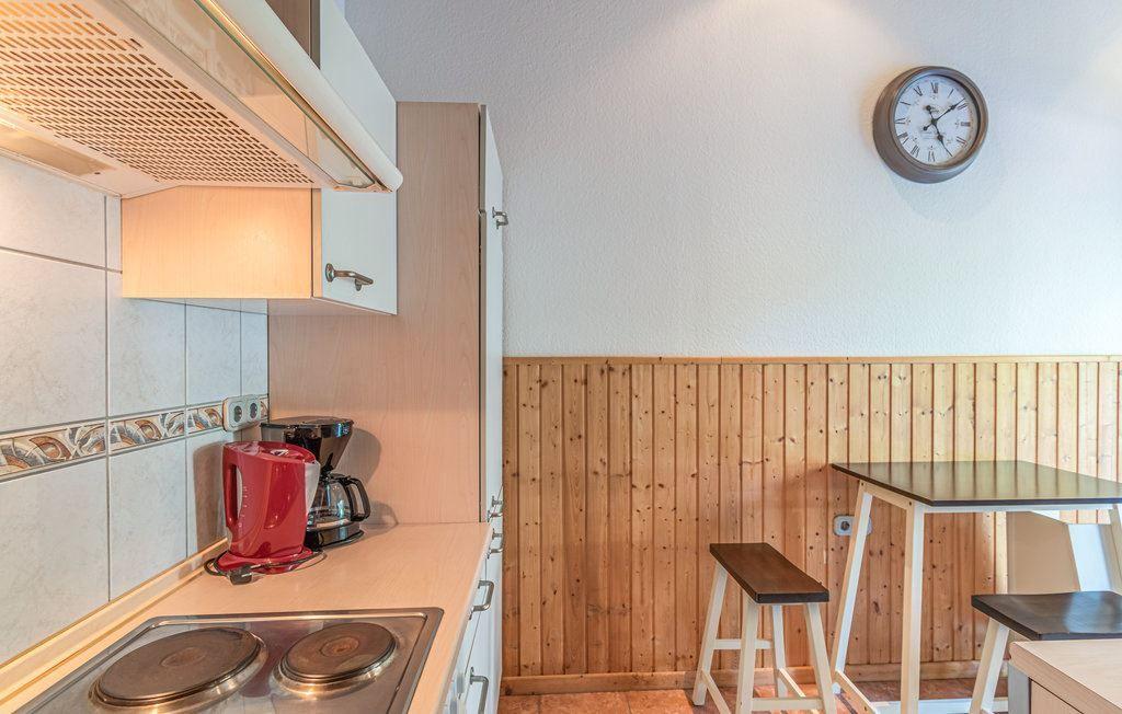 Küche mit Arbeitsplatte, Herd und Tisch mit Stühlen an Holzwand.