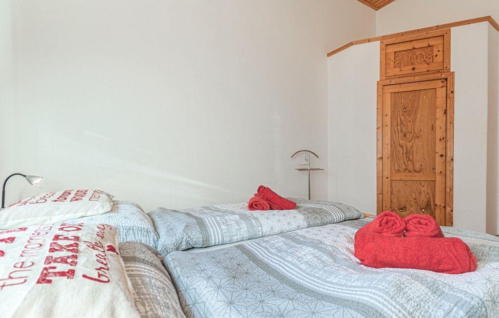 Schlafzimmer mit Bett, roten Handtüchern und Holztür.