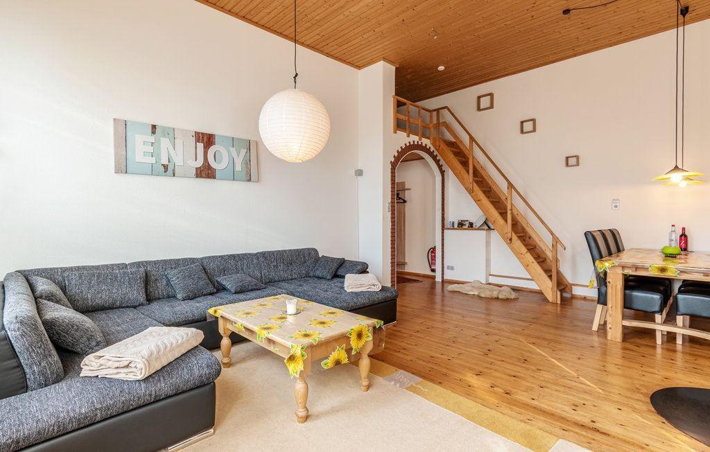 Wohn- und Essbereich mit Sofa, Tisch und Holztreppe.