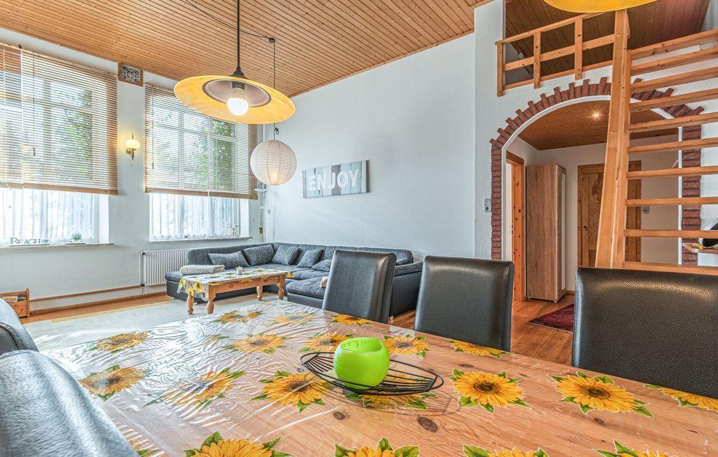 Esszimmer mit Sonnenblumen-Tischdecke und Sitzbereich mit Sofa und Tisch.