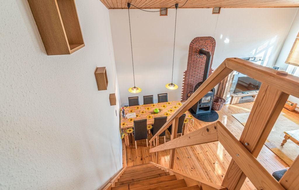 Von oben: Holztreppe, Essbereich mit Tisch und Stühlen, Kaminofen und Wohnbereich.