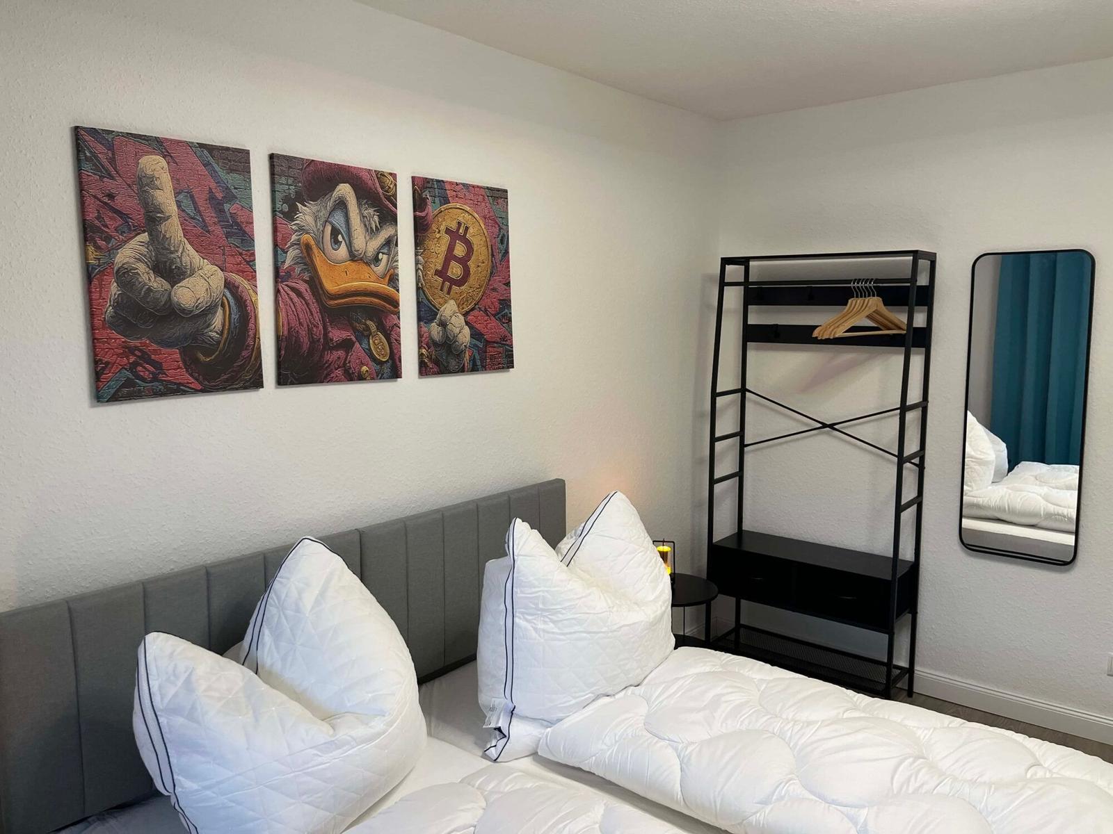 Schlafzimmer mit Bett, Kleiderschrank und Wandbildern