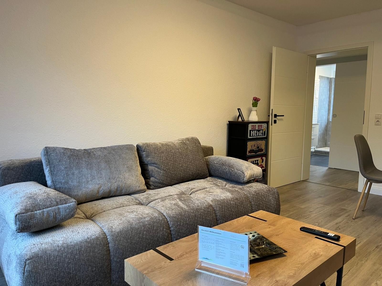 Wohnzimmer mit Sofa, Couchtisch und Blick in die Küche.