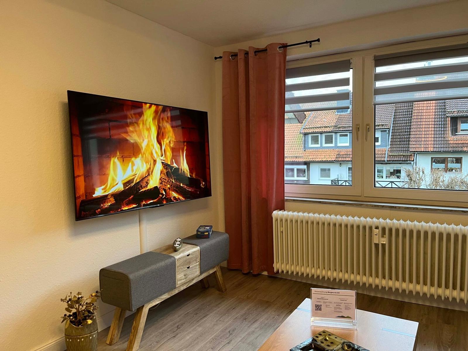 Wohnzimmer mit Fernseher, Fenster und Heizkörper