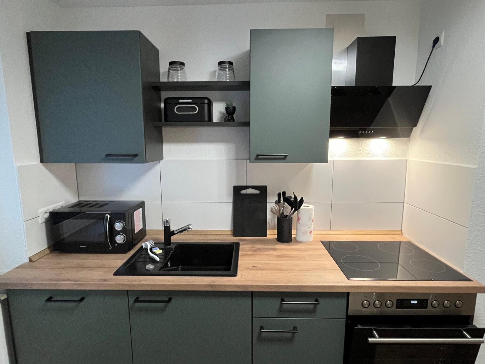 Küche mit Holz Arbeitsplatte, Dunstabzug, Herd und Mikrowelle.