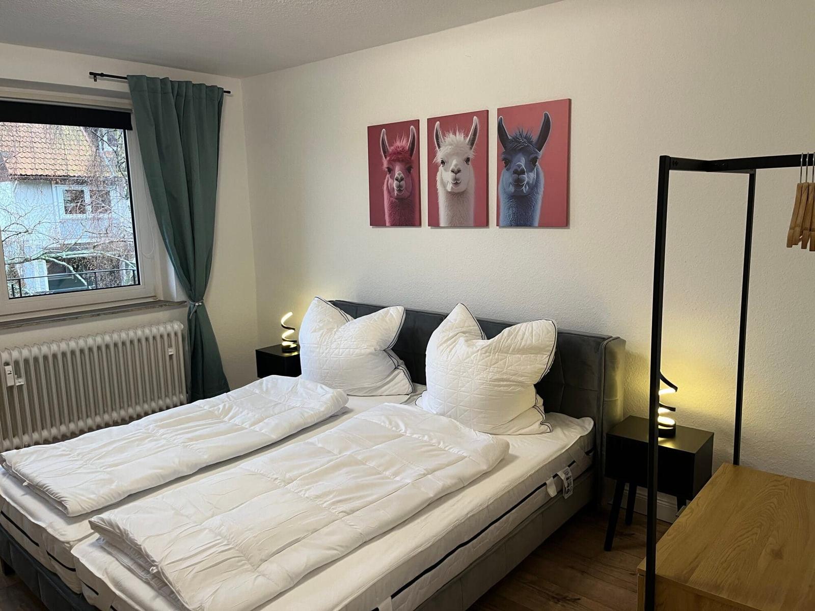 Schlafzimmer mit Doppelbett, Wandbildern und Fenster mit Blick.