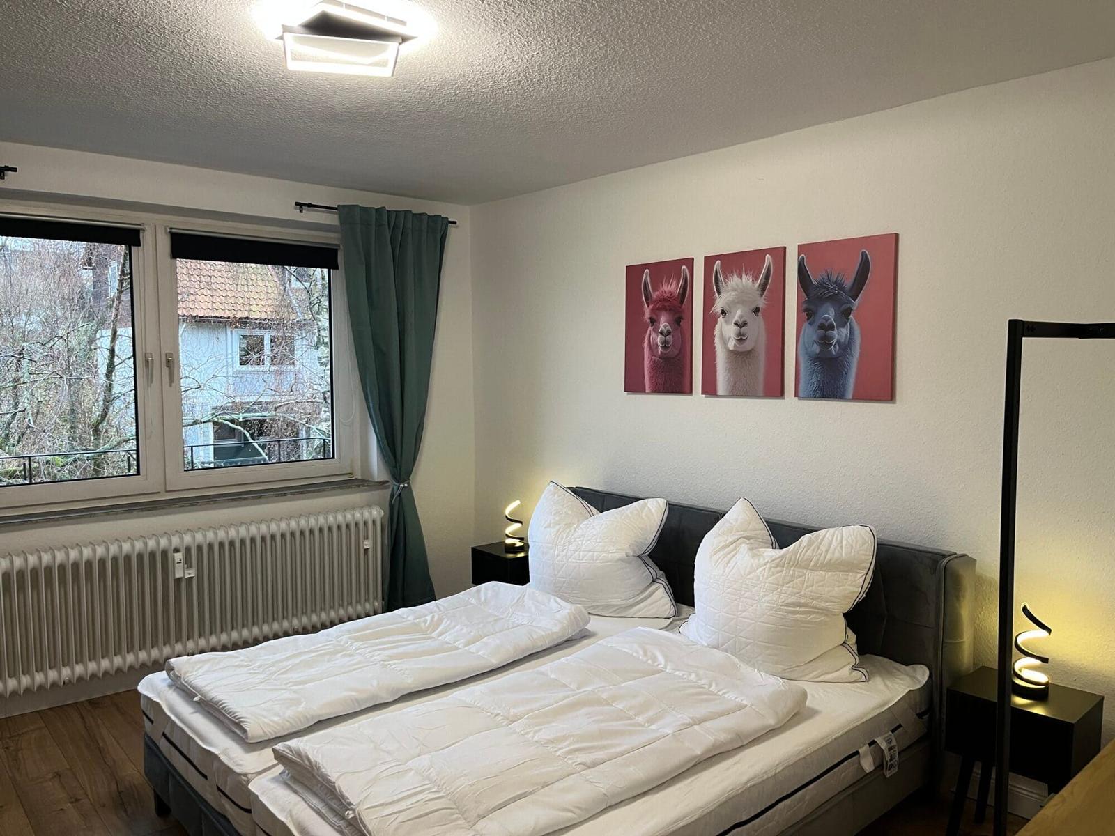Schlafzimmer mit Doppelbett, Wandbildern von Lamas und Fenster mit Blick.