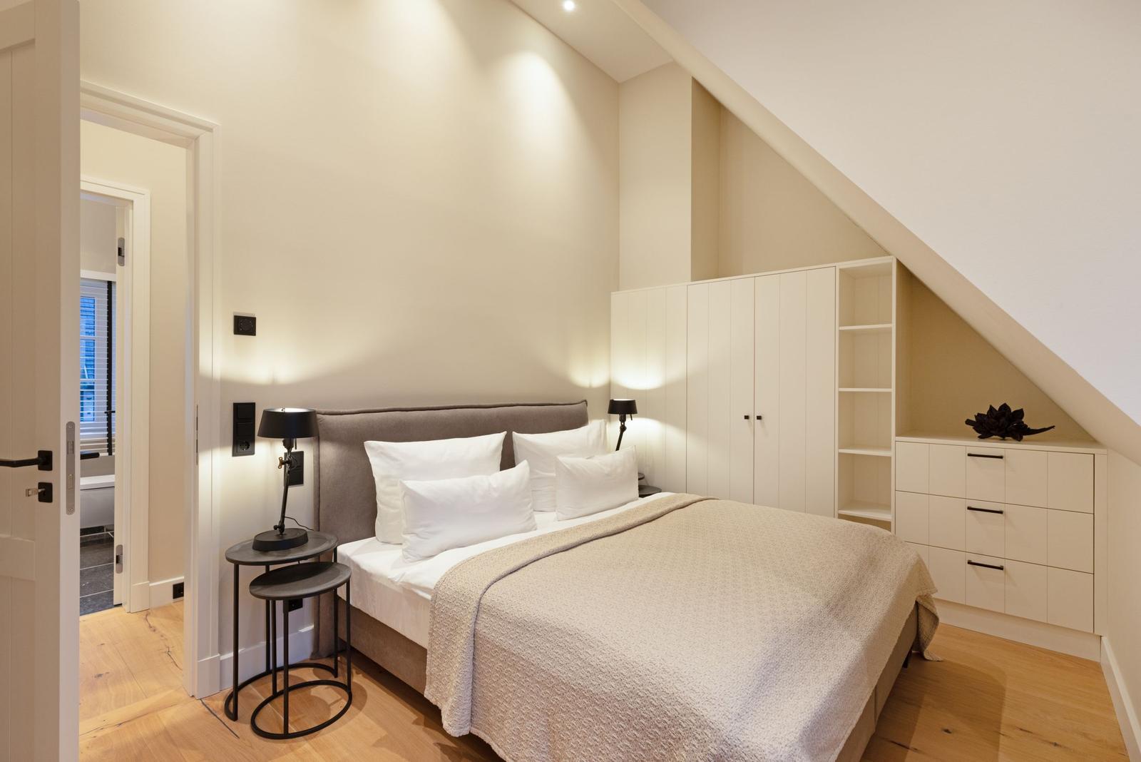 Schlafzimmer mit Dachschräge, Bett, Nachttisch und Kleiderschrank.
