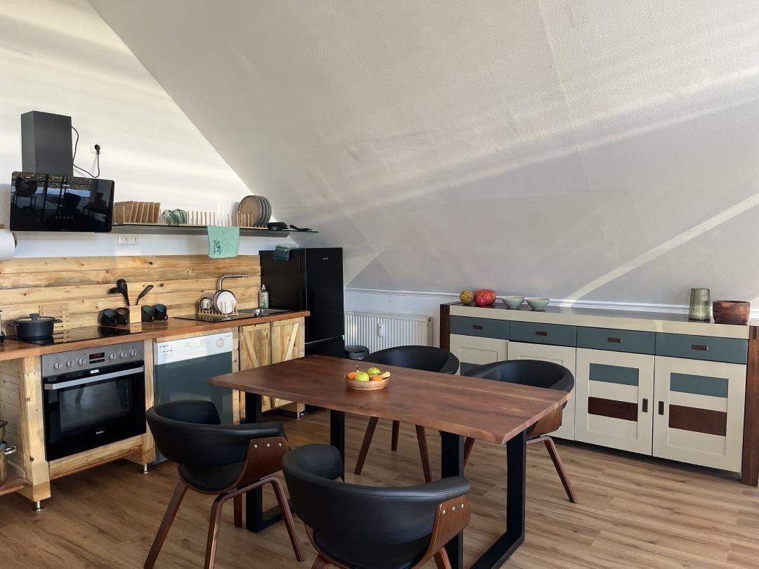 Kitchen with dining area under sloped ceilings, wooden surfaces, and modern furniture.