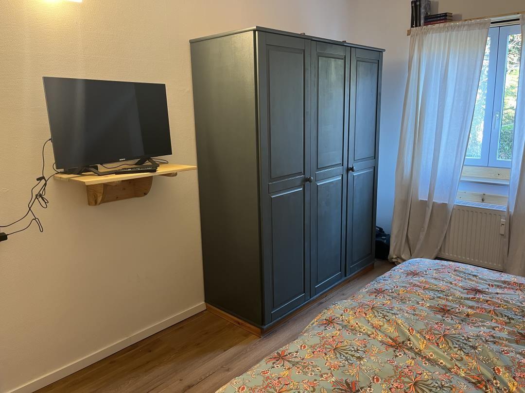 Bedroom with bed, wardrobe, and wall-mounted TV