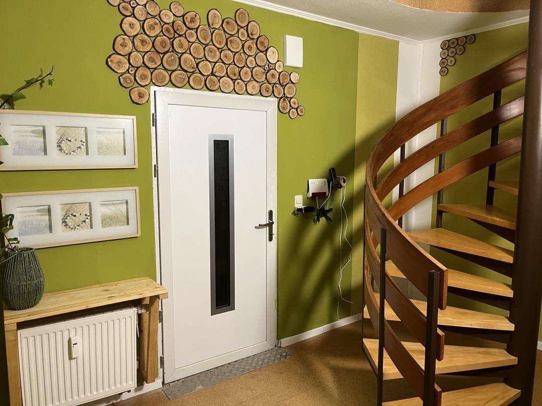 Entrance area with spiral staircase, green wall, and wood decor.