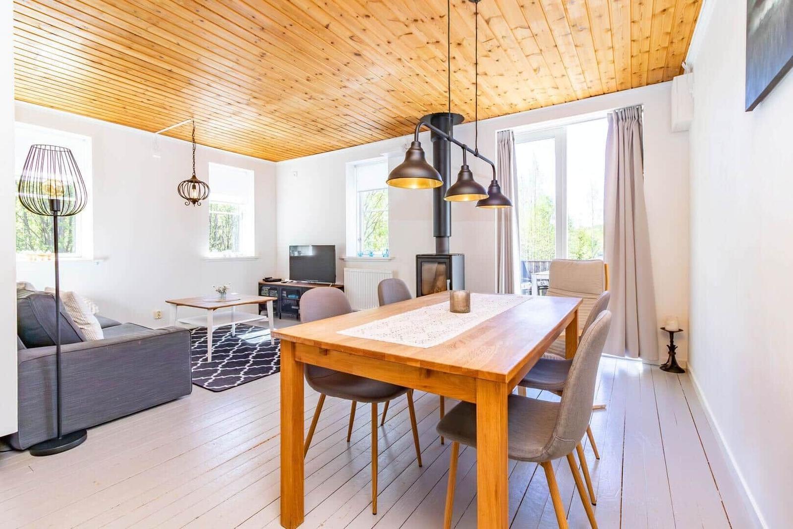 Esszimmer mit Holztisch, Stühlen und Küchenzeile. Wohnbereich mit Sofa und Fernseher.