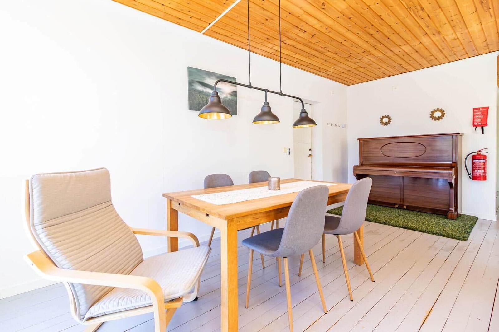Esszimmer mit Holztisch, Stühlen und Klavier an der Wand.