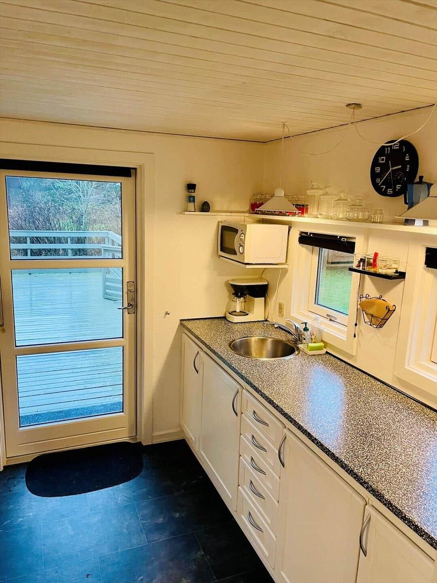 Kitchen with countertop, sink, microwave, and coffee maker. Door leads to terrace.
