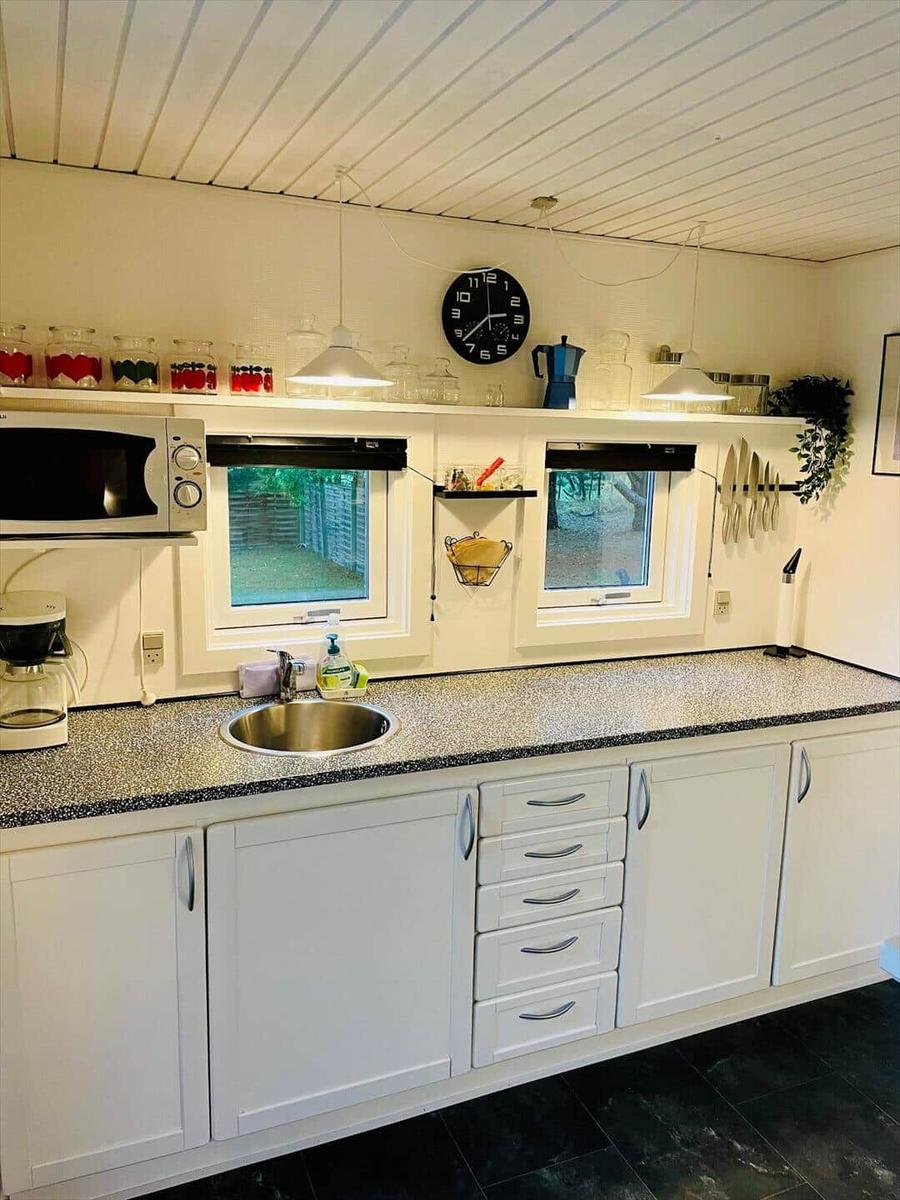 Kitchen with white cabinets, countertop, and windows to the garden.