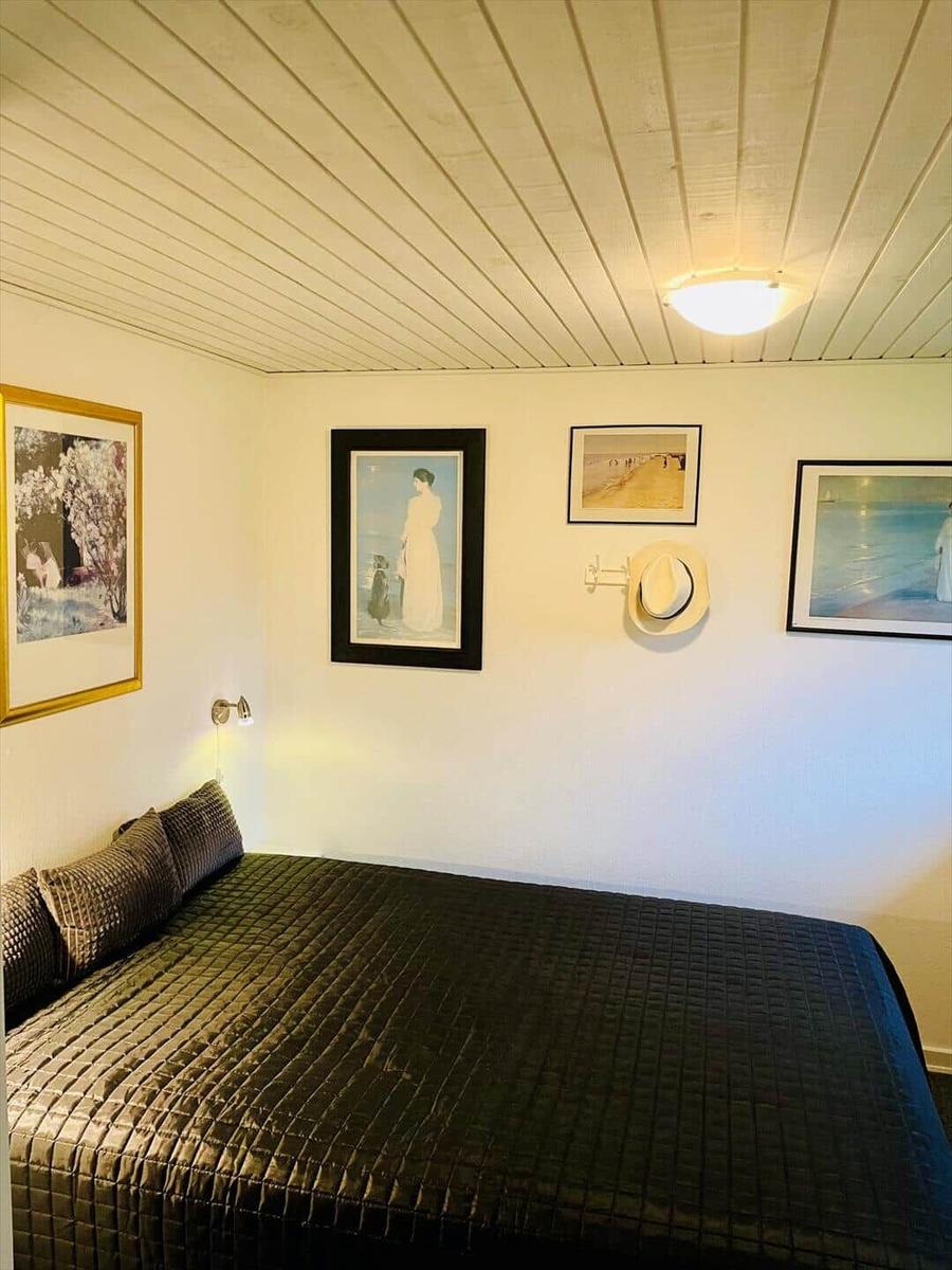 Bedroom with bed, wall art, and hat rack on the wall.