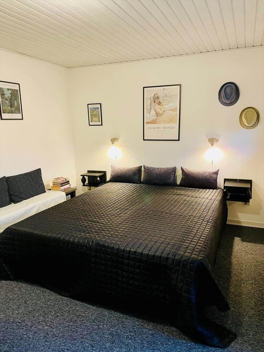 Bedroom with large bed, wall art, and nightstands with lamps.