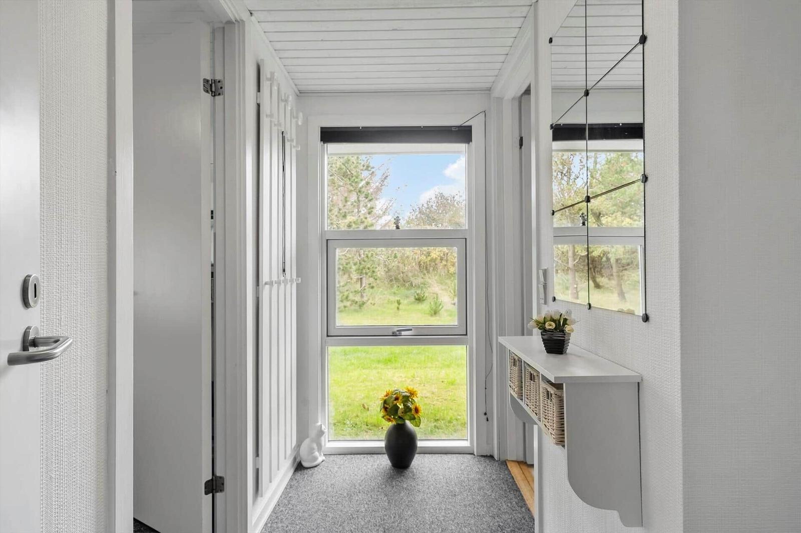 Entryway with window, mirror, and vase with sunflowers.