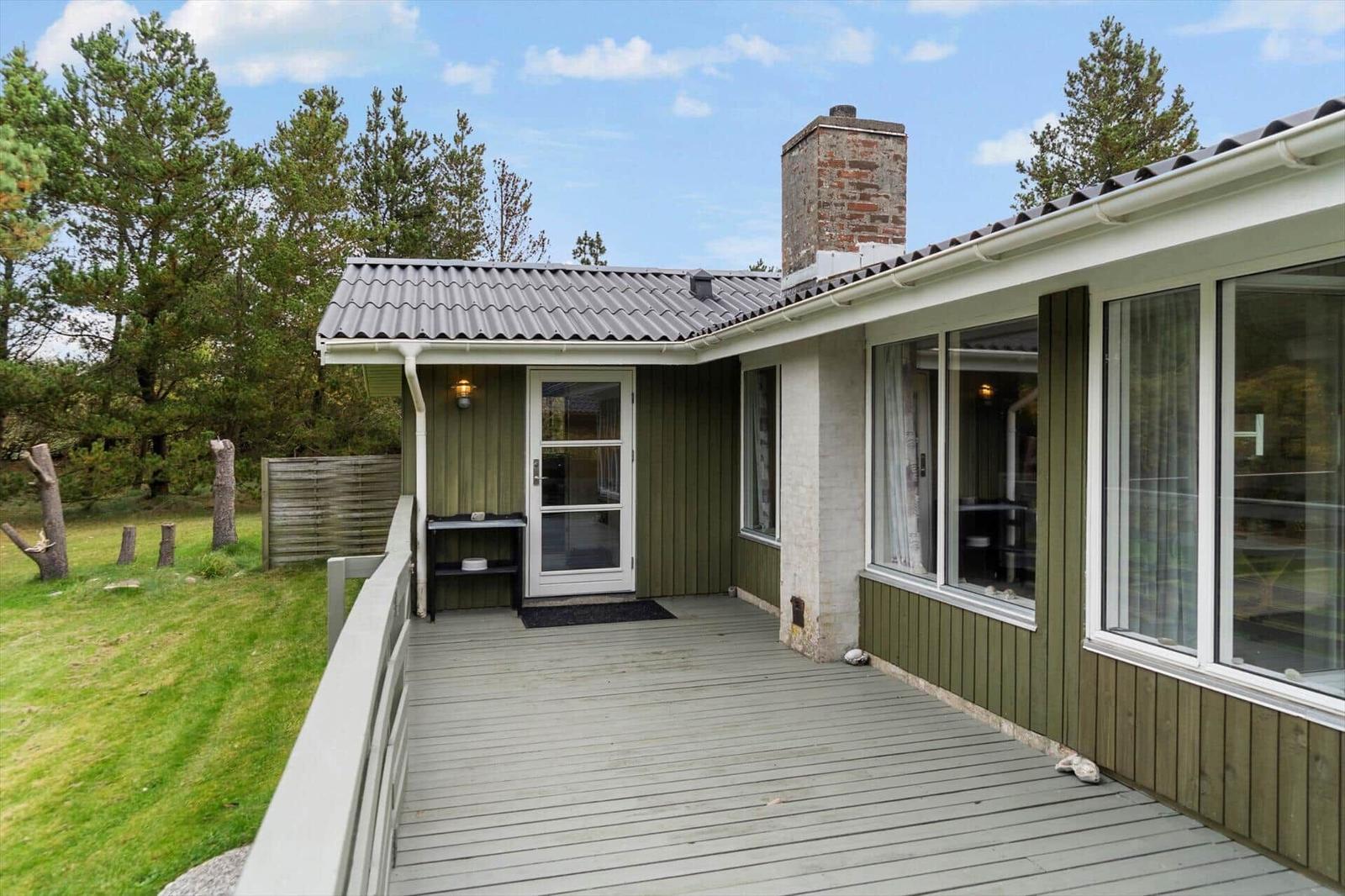 Wooden terrace with entrance door and large window area at modern house.