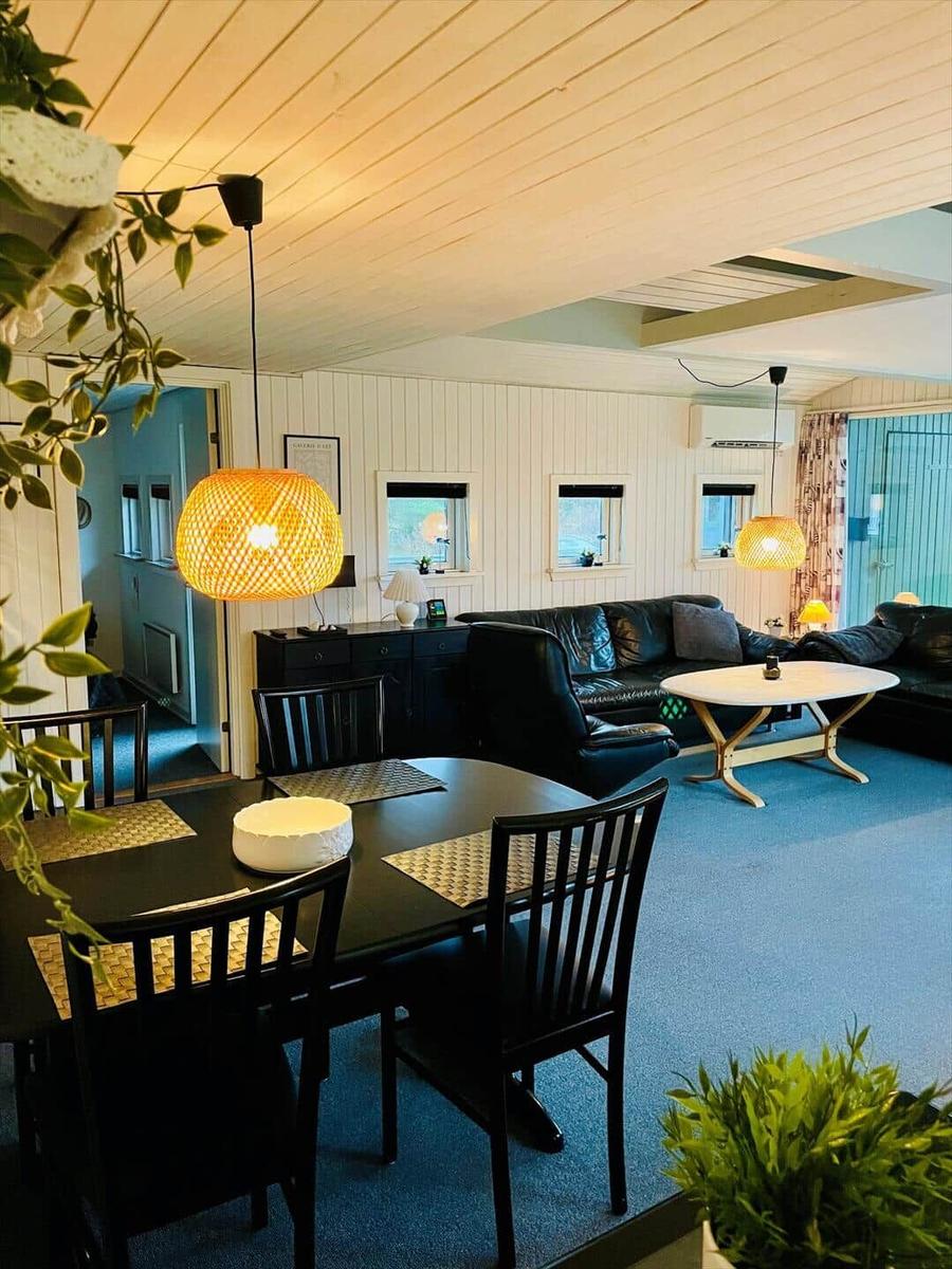 Dining area with table and chairs. Living area with sofa and coffee table. Ceiling and walls are panelled white.