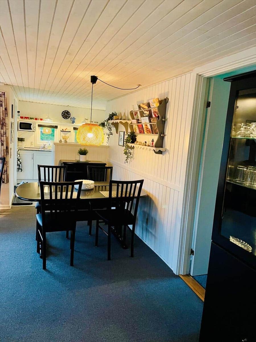 Dining room with table, chairs, and kitchen area in the background.