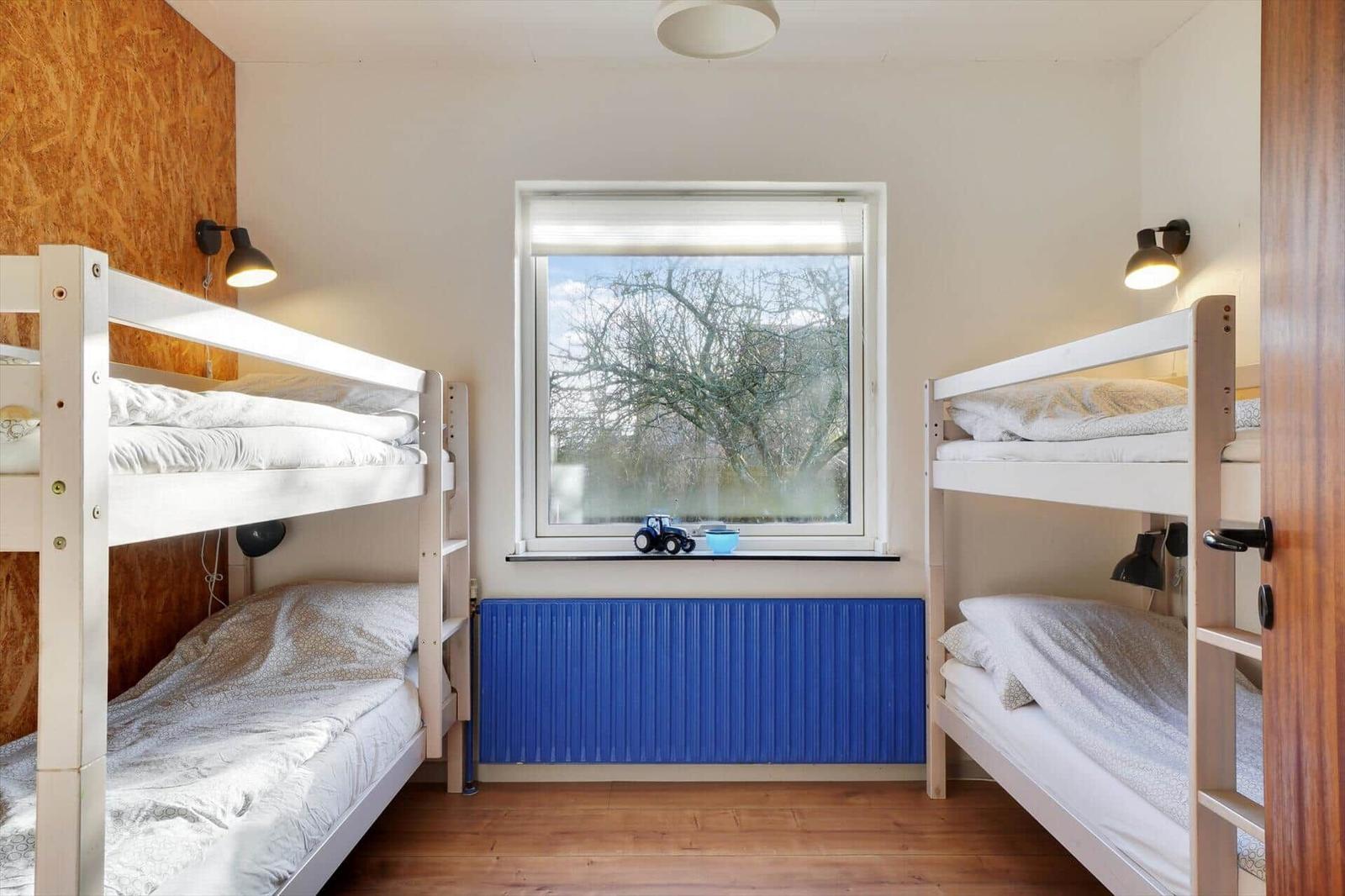 Two bunk beds with window and blue radiator.