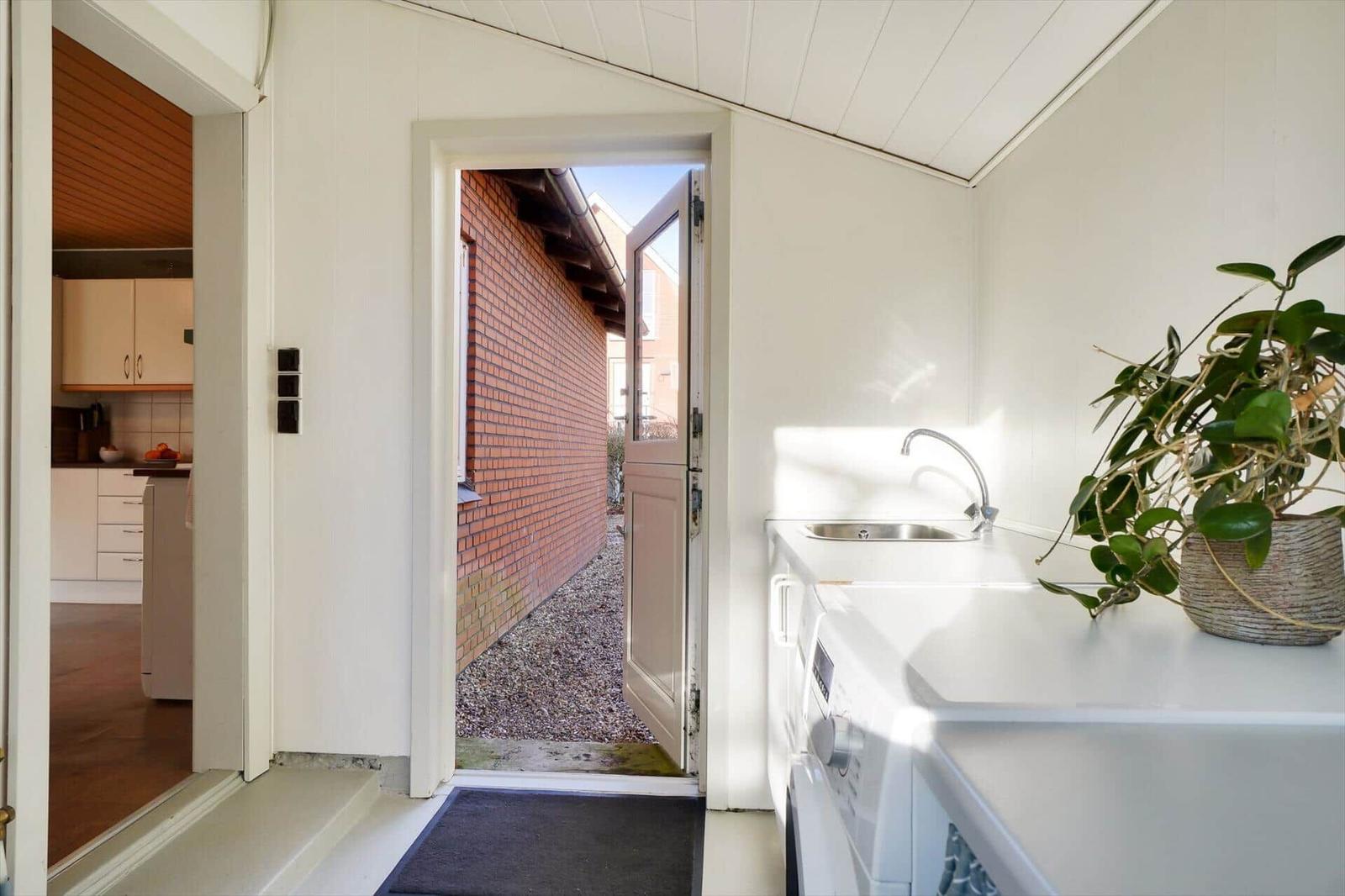 Backyard with washing machine and sink. Entrance to the kitchen.