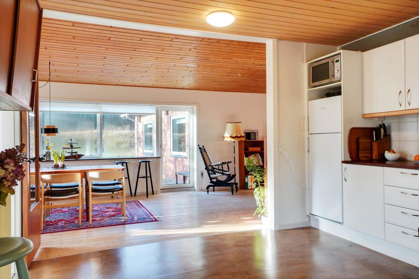 Kitchen with white cabinets and dining area with wooden table and chairs.
