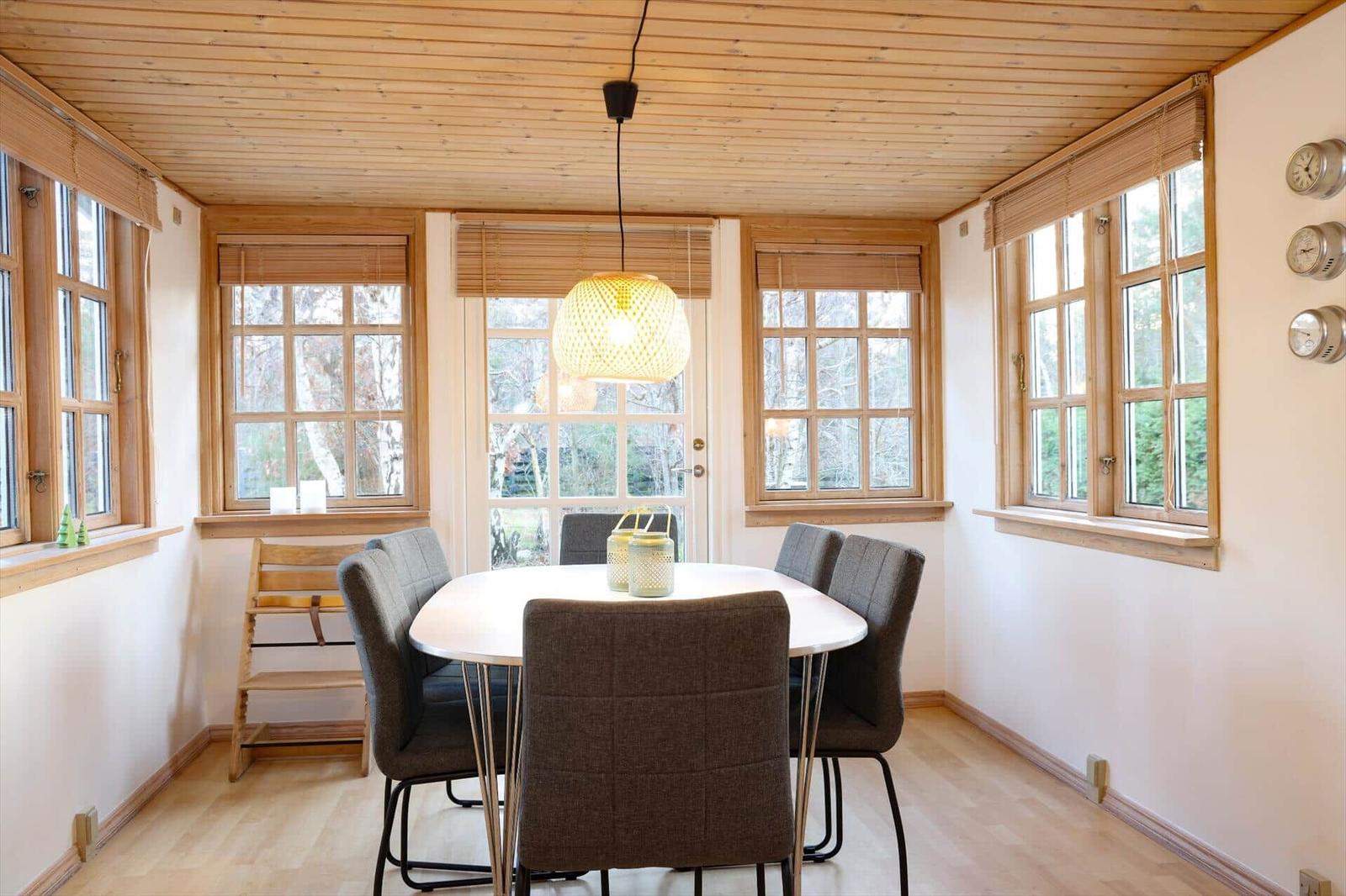 Dining room with round table, chairs, and wooden windows. Ceiling and floor are wooden.