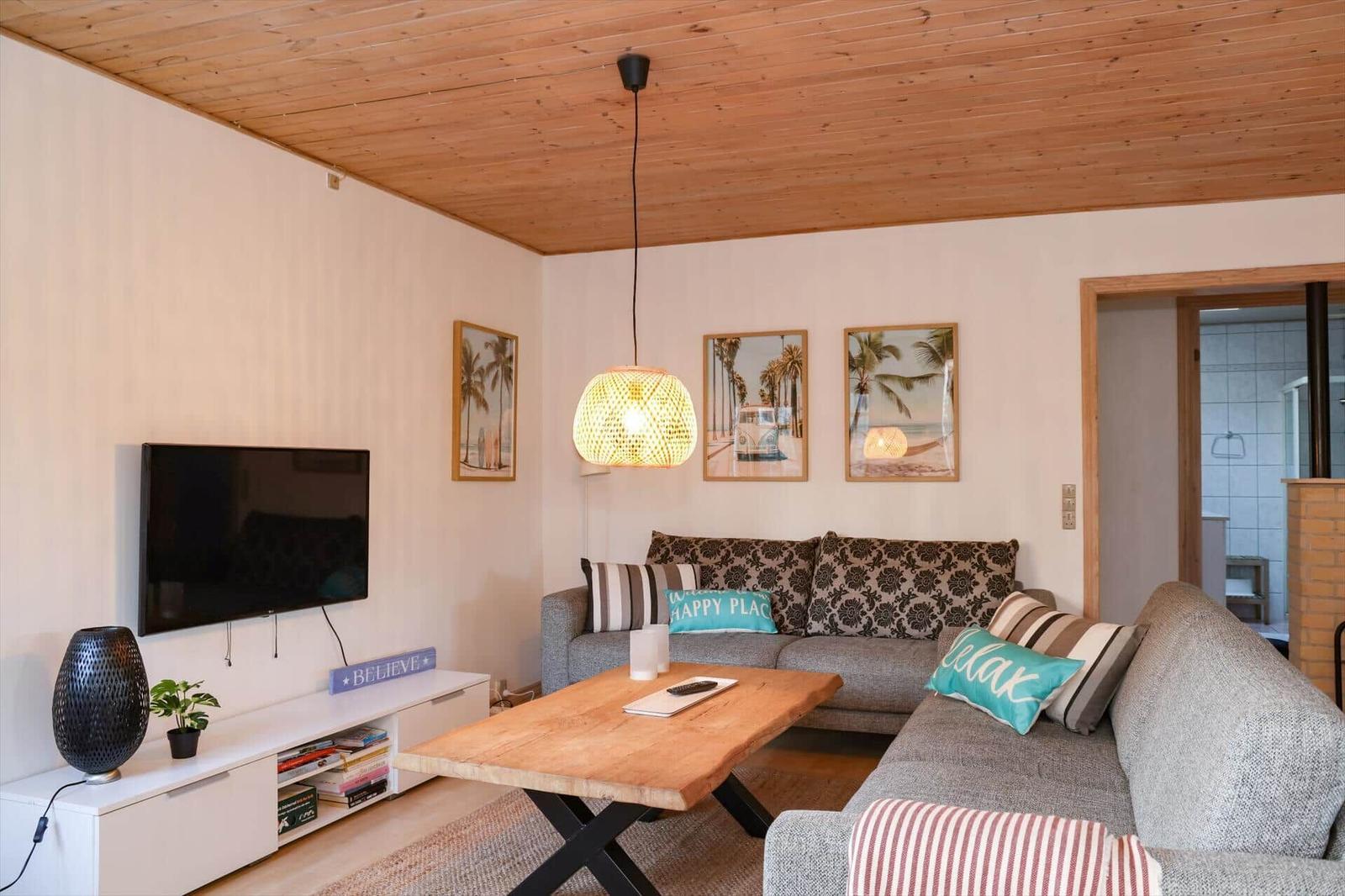 Living room with sofa, wooden table, and TV mounted on the wall.