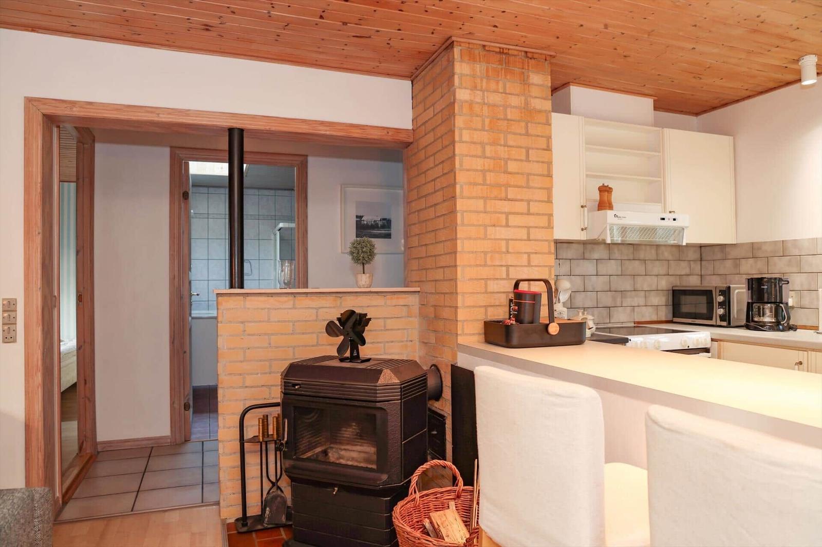 Kitchen with wooden ceiling, wood stove, and view into the bathroom.