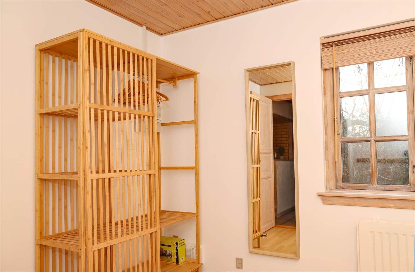 A room with wooden shelving, door, and window. Wooden ceiling and wall color.