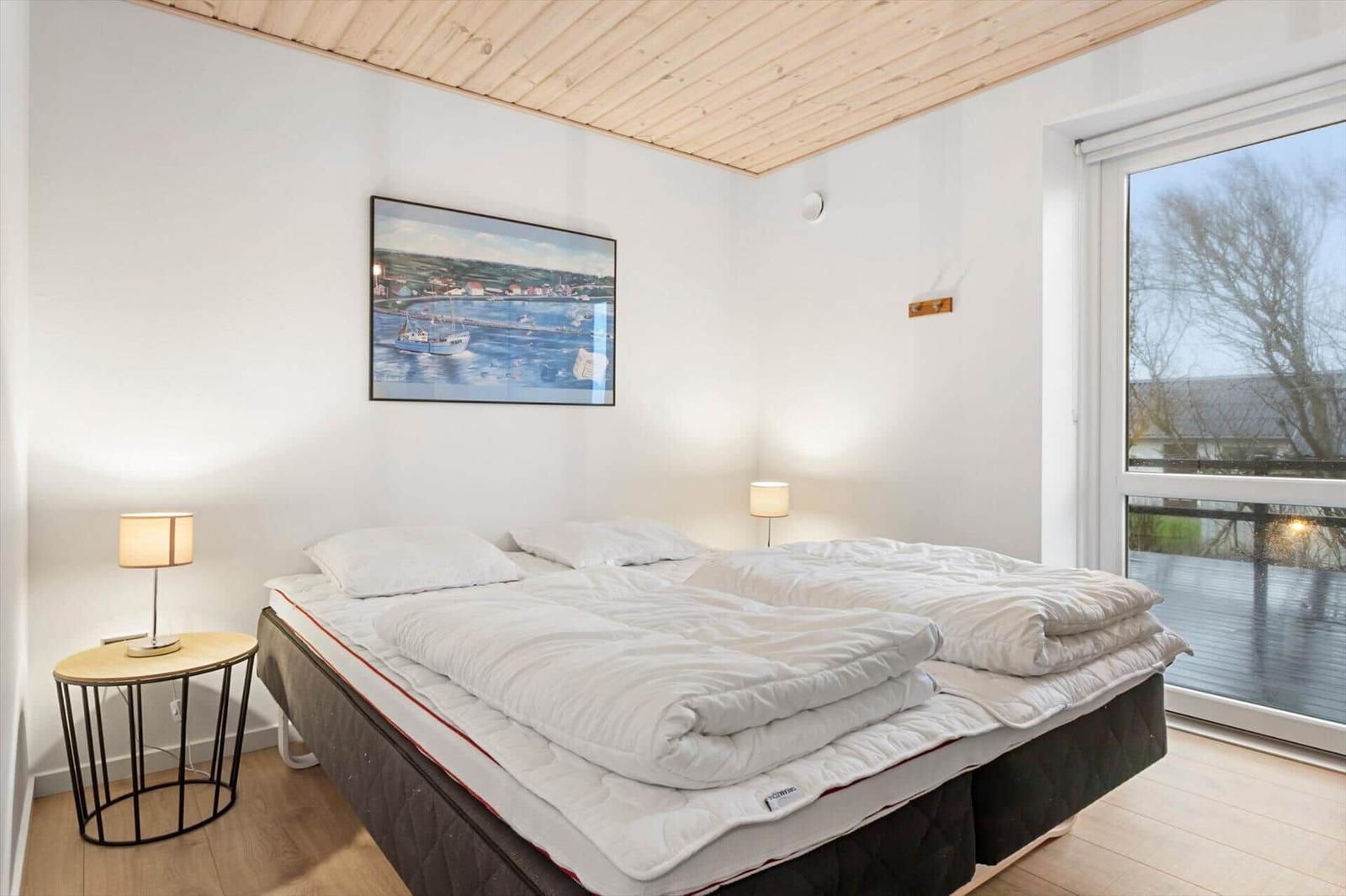 Bedroom with double bed, two bedside tables, and window to terrace.